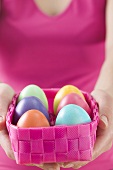 Woman holding basket of coloured Easter eggs