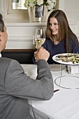 Couple clinking glasses of white wine in restaurant
