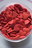 Pink sugar hearts in glass bowl (overhead view)