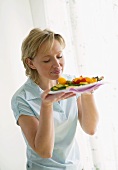 Woman smelling grilled vegetables on plate
