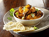 Curry with coriander leaves and poppadoms