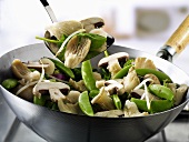 Vegetables and mushrooms in wok and on spatula