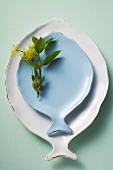 Weisser und blauer fischförmiger Teller dekoriert mit Kräutern