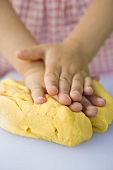 Child's hands kneading dough