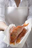 Woman holding fresh red mullet on paper