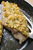 Fish fillets with bread crust in frying pan