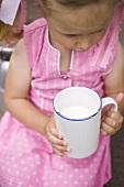 Kleines Mädchen hält Becher Milch