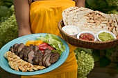 Woman serving Asian platter and basket of accompaniments