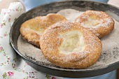 Hands holding Auszogene (Bavarian doughnuts) in frying pan