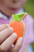 Child's hand holding Easter biscuit with bite taken