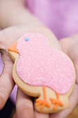 Child's hands holding Easter biscuit (pink chick)