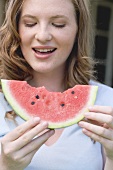 Young woman holding a slice of watermelon with bites taken