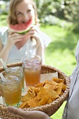 Person holding basket of drinks and tortilla chips