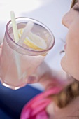 Woman holding a glass of lemonade with straws