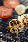 Garlic and tomatoes on a barbecue grill rack