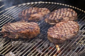Four beef steaks on a barbecue