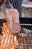 Putting raw steak on barbecue
