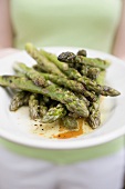 Woman holding a plate of grilled green asparagus
