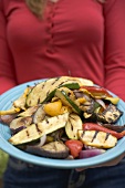 Woman holding a plate of grilled vegetables