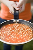 Person holding a pan of baked beans