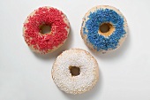 Drei Doughnuts mit Zuckerstreuseln (rot, blau, weiss)