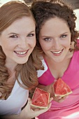 Two women holding pieces of watermelon