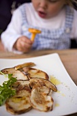Fried cep slices, child with chanterelle behind