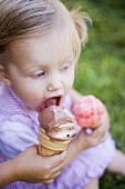 Child's hand offering small girl a lick of ice cream
