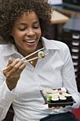 Frau isst Sushi im Büro