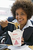 Woman in office eating Asian noodle dish