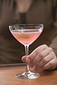 Woman with glass of pink Martini with olive