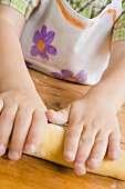 Child forming dough into a roll