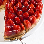 Strawberry flan, partly sliced, with piece on server