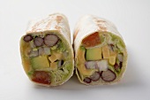Two wraps filled with avocado, lettuce and cheese