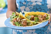 Woman holding plate of two tacos