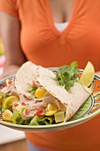 Woman serving plate of filled tortillas
