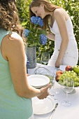 Zwei Frauen decken den Tisch für eine Gartenparty