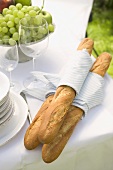 Baguettes, wine glasses and fruit on table out of doors