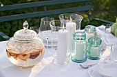 Peach punch, windlights and glasses on table in garden