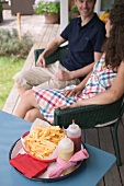 Paar sitzt auf Terrasse, Pommes frites im Vordergrund