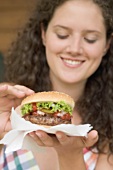 Woman holding hamburger on paper napkin