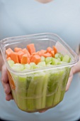 Woman holding plastic container of celery and carrots