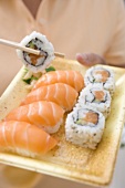 Woman holding sushi on plastic tray