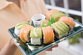Woman holding sushi platter with soy sauce