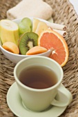 Teetasse, frische Früchte und Handtuch im Korb