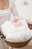 Woman holding white bathrobe and orchid in basket