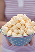 Frau hält Popcorn in Schale mit Sterndeko (4th of July, USA)