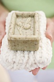Woman holding olive soap on towel