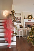 Frau trägt Schachteln mit Weihnachtsschmuck ins Wohnzimmer