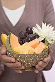 Woman holding bowl of fresh fruit with water lily